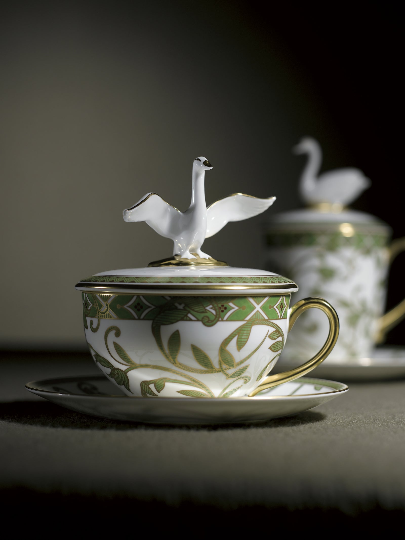 Teacup with decorative design and bird on top, on a white background