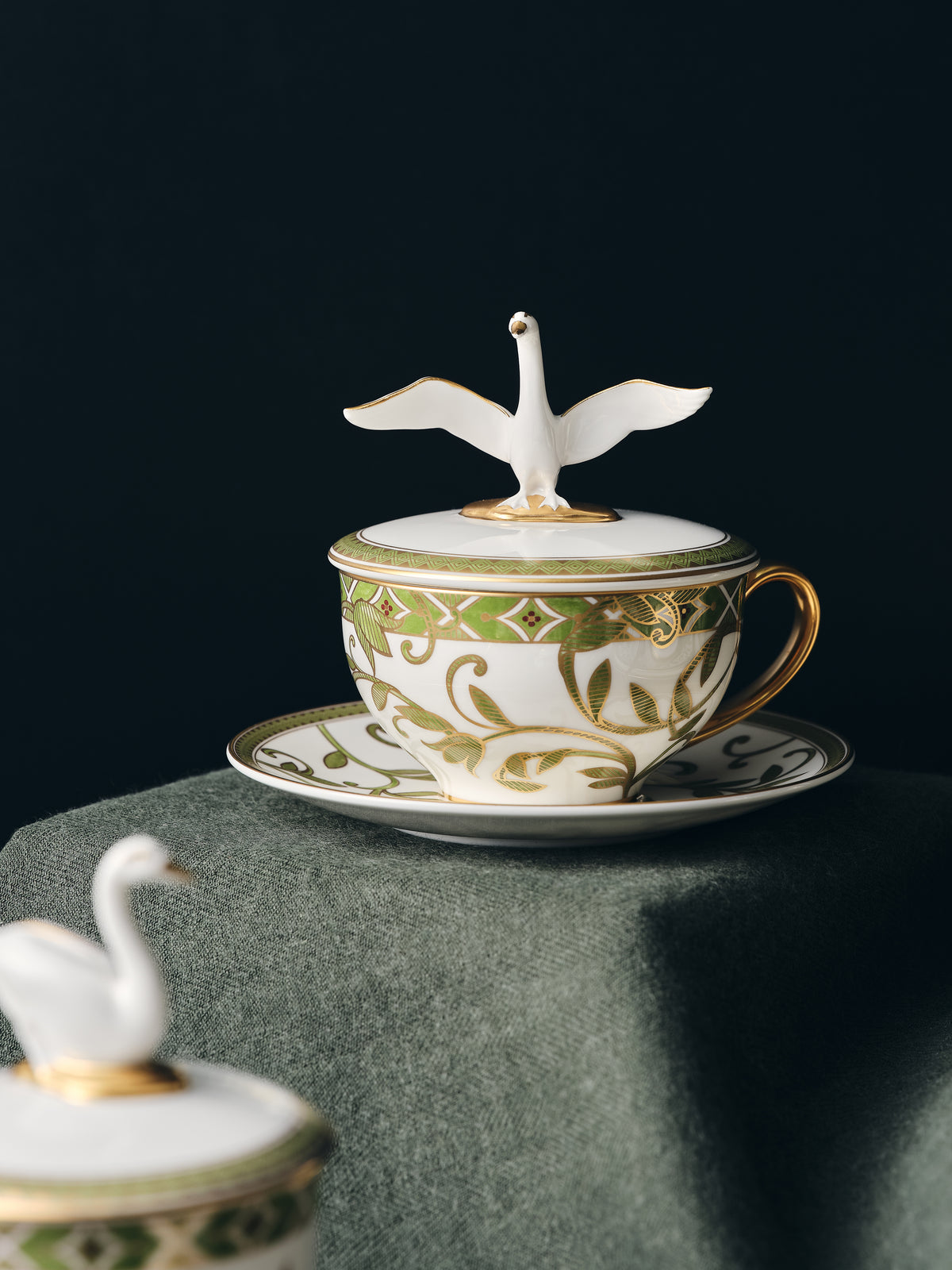 Decorative teacup with swan design on a dark background